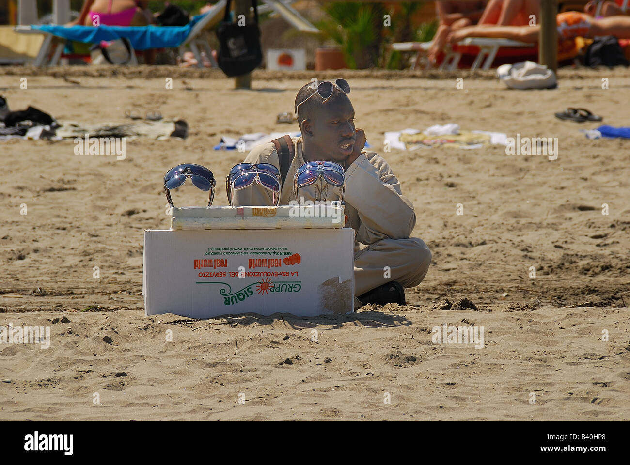 Veneto, Italia,un inmigrante está vendiendo gafas de Rosolina playa. Foto de stock