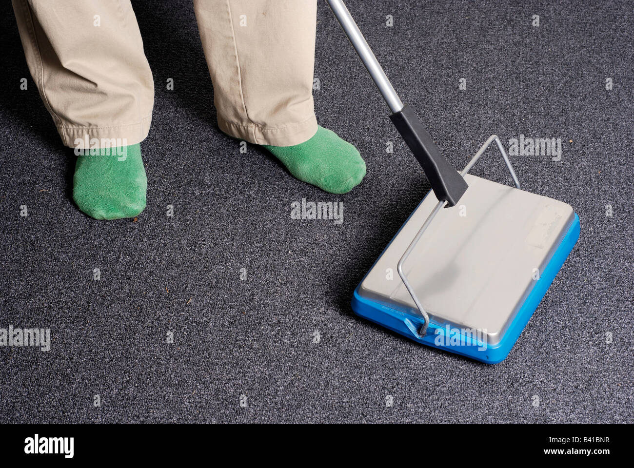 Un hombre respetuoso con el medio ambiente utiliza una escoba para limpiar  alfombras contemporáneas sin usar electricidad Fotografía de stock - Alamy