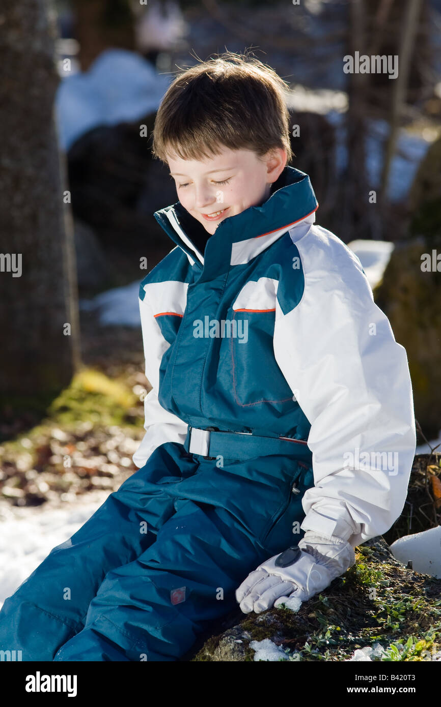 Un sonriente niño plantea fuera en ropa de esquí y guantes. Retrato de tres  cuartos Fotografía de stock - Alamy