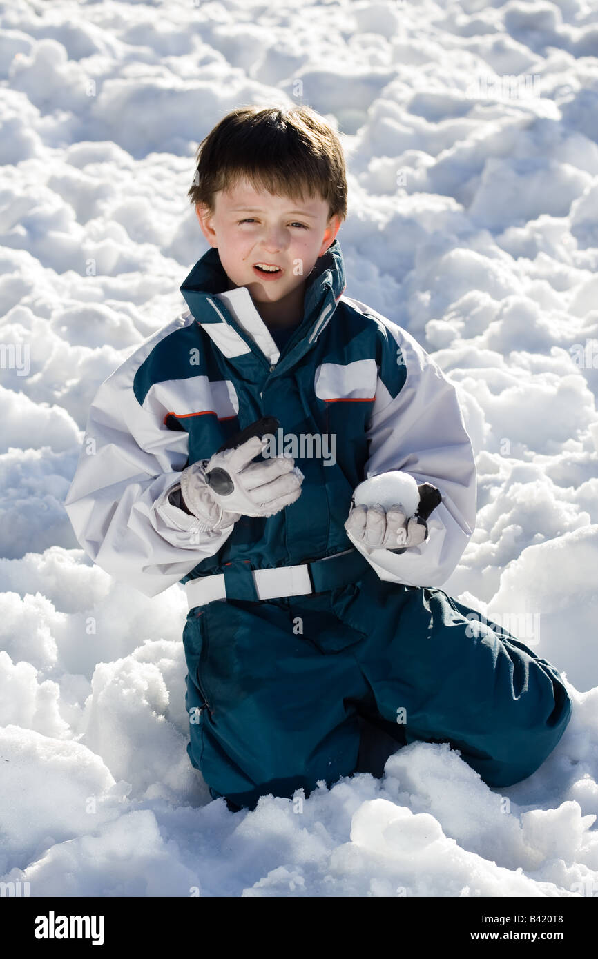 Retrato de un niño sosteniendo una bola de nieve que él está usando un traje  de esquí azul y blanco fuera en la nieve Fotografía de stock - Alamy