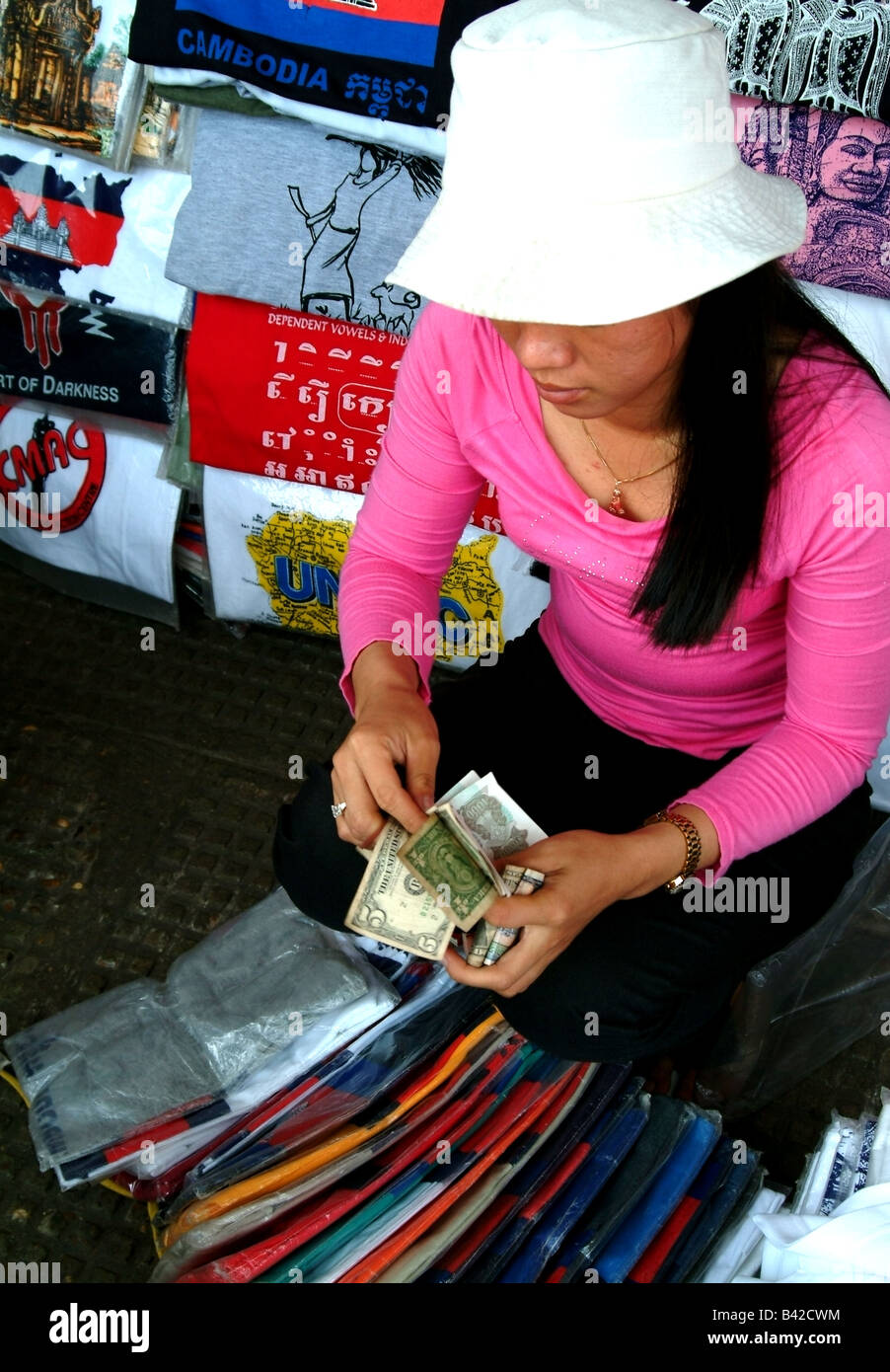 Mujer vendiendo camisetas en mercado en Phnom Penh, Camboya Foto de stock
