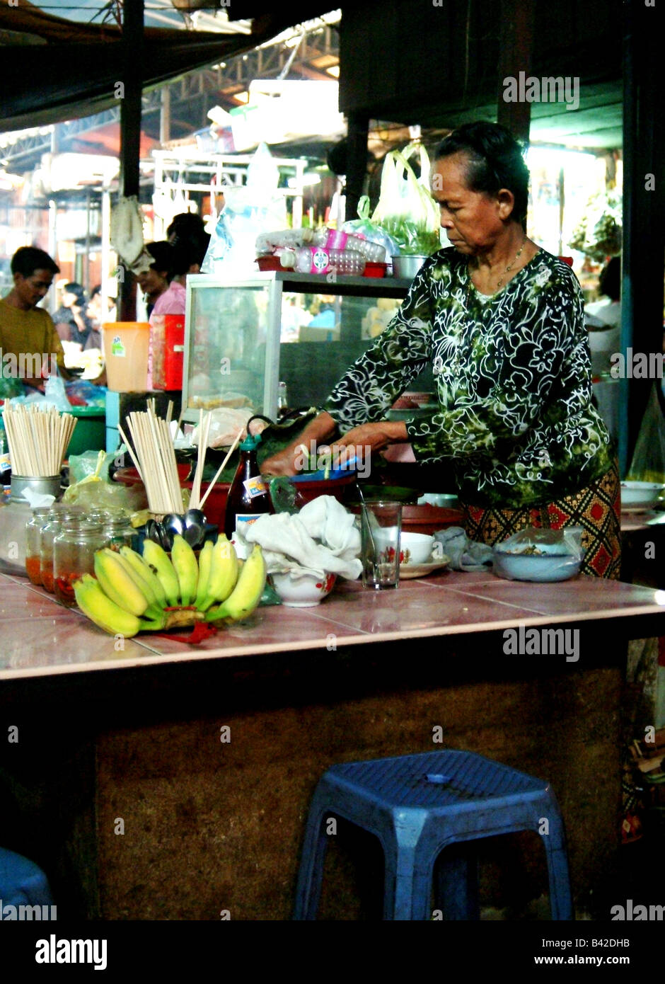 Mujer cocinando comida en un puesto en un mercado, en Phnom Penh, Camobdia Foto de stock