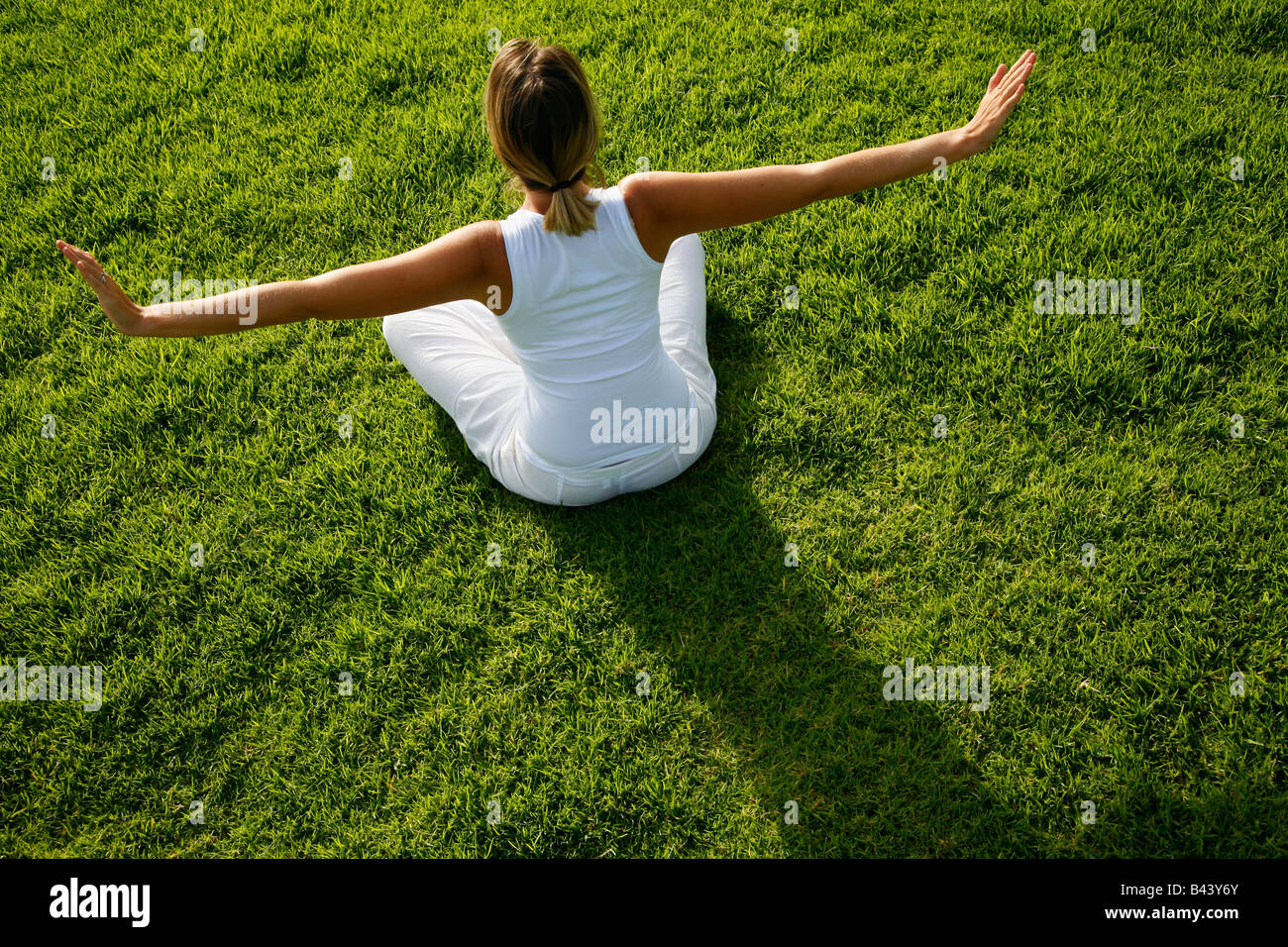 Yoga al amanecer sobre el césped Foto de stock