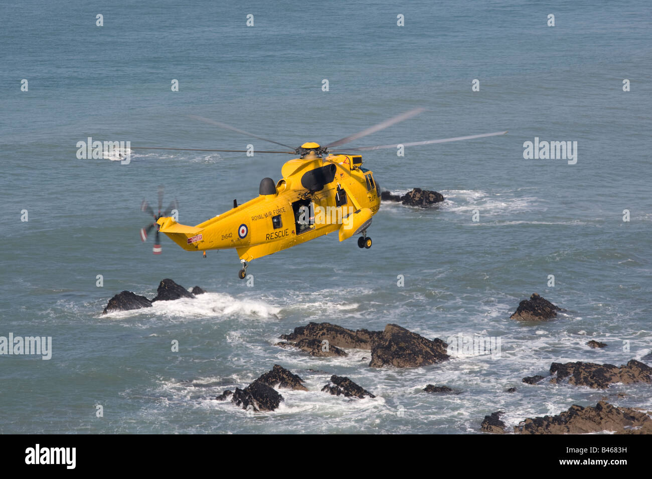 RAF helicóptero de rescate en el mar de aire flotando sobre rocas cerca de la Bahía de Widemouth Bude Cornualles UK Foto de stock