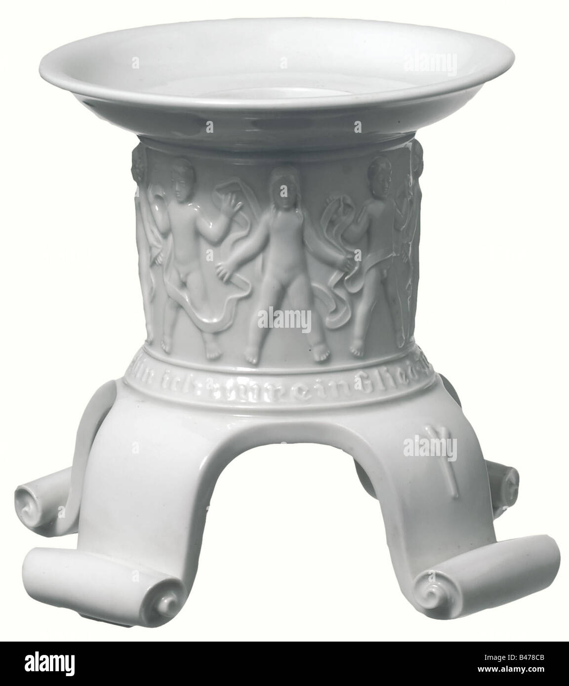 Un candelabro de kinderfries., porcelana blanca vidriada con un kinderfries en el relieve que corre alrededor del eje sobre el rollo de la inscripción, 'En der Sippe ew'ger Kette bin ich nur ein Glied' (En la familia de la cadena eterna, soy sólo un eslabón). Bandeja de goteo saliente. Cuatro pies curvos con extremos enrollados. En cuatro piernas, tres cada una con la "runa de vida" (Algiz rune), la cuarta izquierda en blanco (la pieza ya no se da, sin el nombre del niño). Hay una Marca apenas legible del fabricante impresionada en la parte inferior junto con una firma del facsímil, 'H. Himmler'. Altura 14.5 cm. Ra, Foto de stock