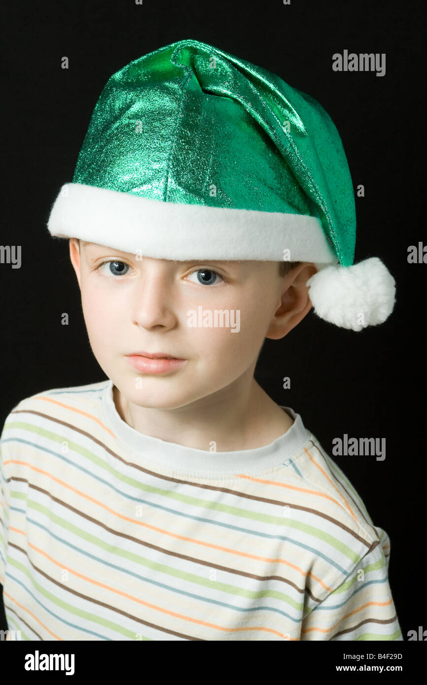 Un joven con un verde Navidad elf hat y white tassle; cabeza y hombros retrato aisladas contra un fondo negro Foto de stock