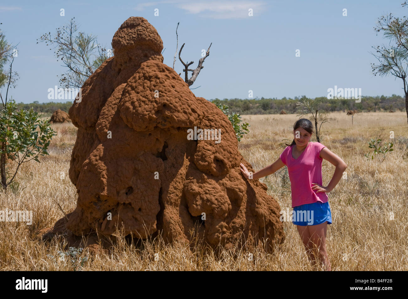Niña de pie junto a un gran nido de termitas para mostrar la escala cerca de Fitzroy Crossing en la región de Kimberley en Australia Occidental Foto de stock