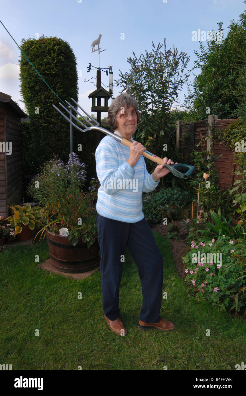 Una mujer de más de setenta posando con una pala de jardinería Foto de stock