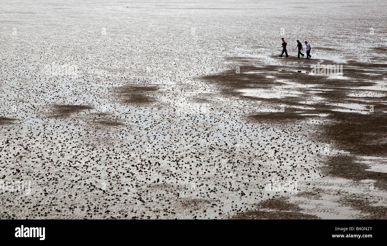 Tres personas andando en Southport playa con marea baja. Foto de stock