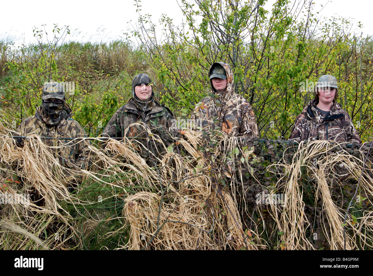 Los adolescentes vestidos de camuflaje ropa en un pato ciego durante un programa para introducir a los jóvenes de caza Foto de stock