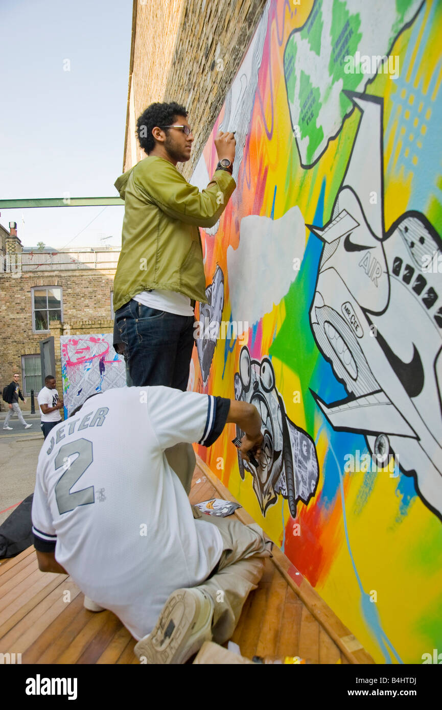 Los jóvenes pintando un gran mural de Nike 90 instructores en una pared en la tienda Nike Hoxton Hackney East London Fotografía stock - Alamy