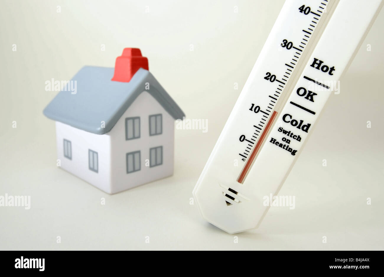 Casa modelo con termómetro de temperatura fría, encienda la calefacción Foto de stock