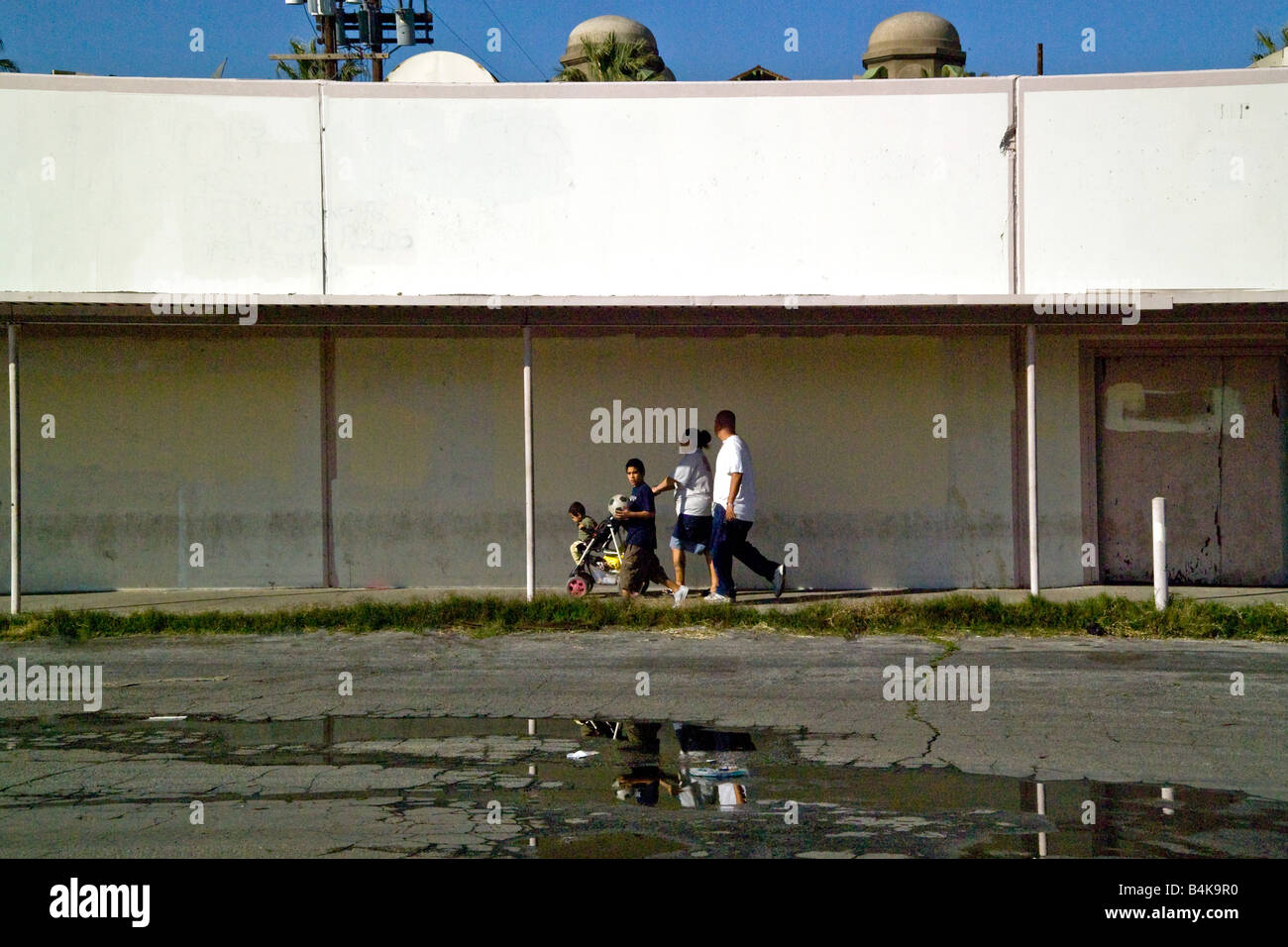 Una familia hispana toma un atajo a través de un centro comercial abandonado en San Bernardino CA una víctima de la cambiante demografía Foto de stock