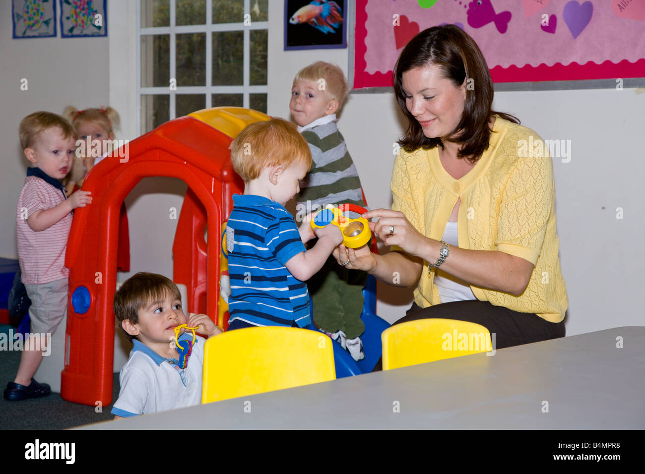 Niños jugando con el profesor en el aula preescolar de la iglesia Foto de stock