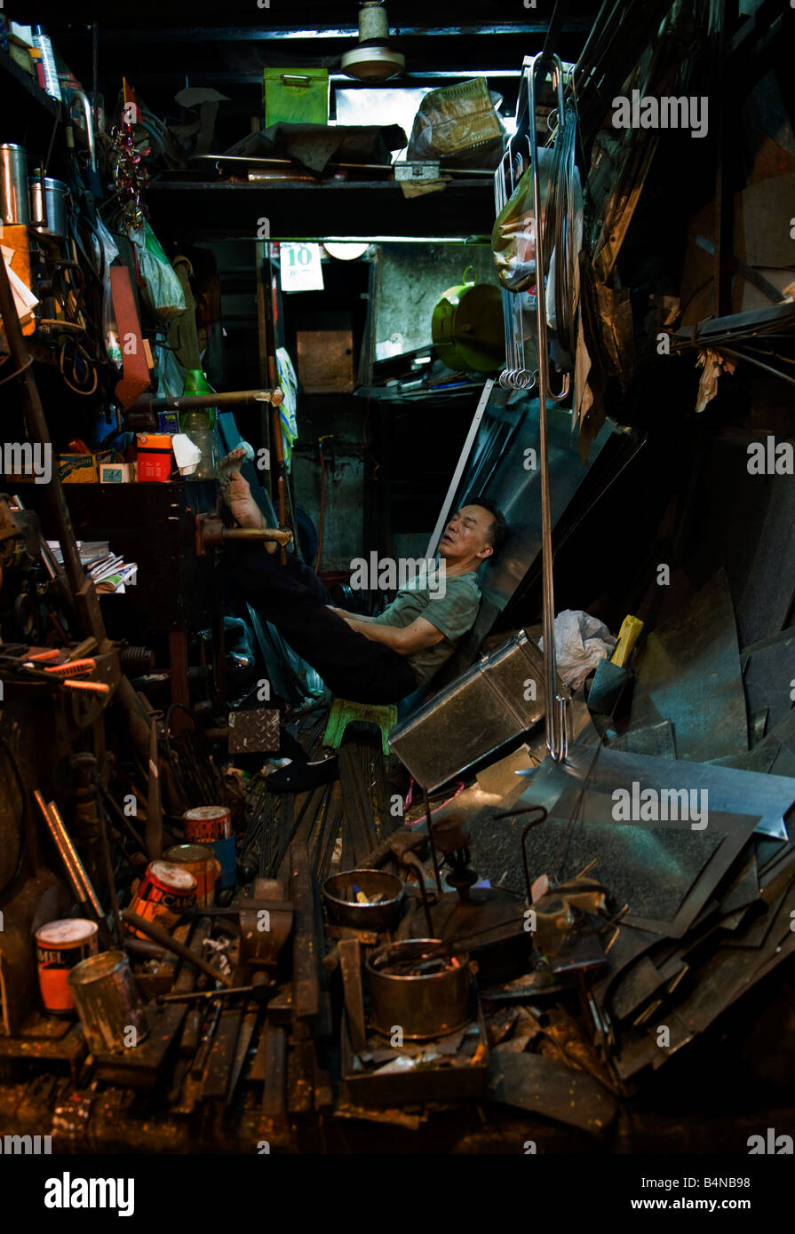 Un hombre duerme en el interior de su tienda de metal en el centro de Hong Kong Foto de stock