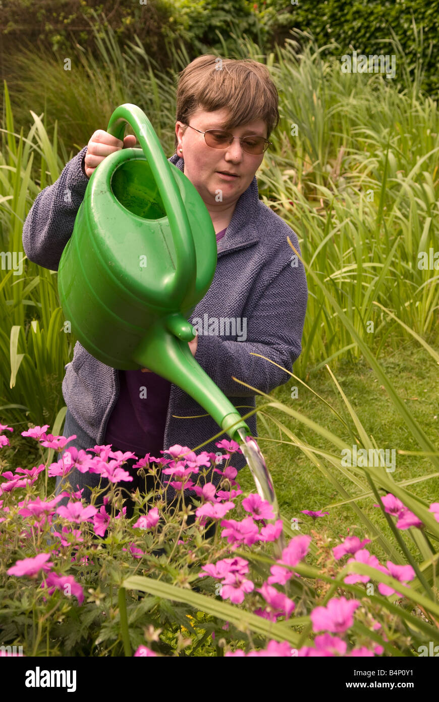 Mujer joven regar las plantas en su jardín, East Sussex, Reino Unido Foto de stock