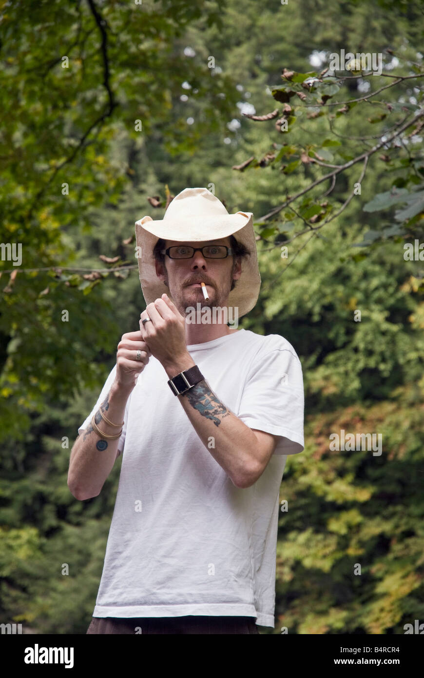 American hombre vestido con sombrero de cowboy enciende un cigarrillo Foto de stock