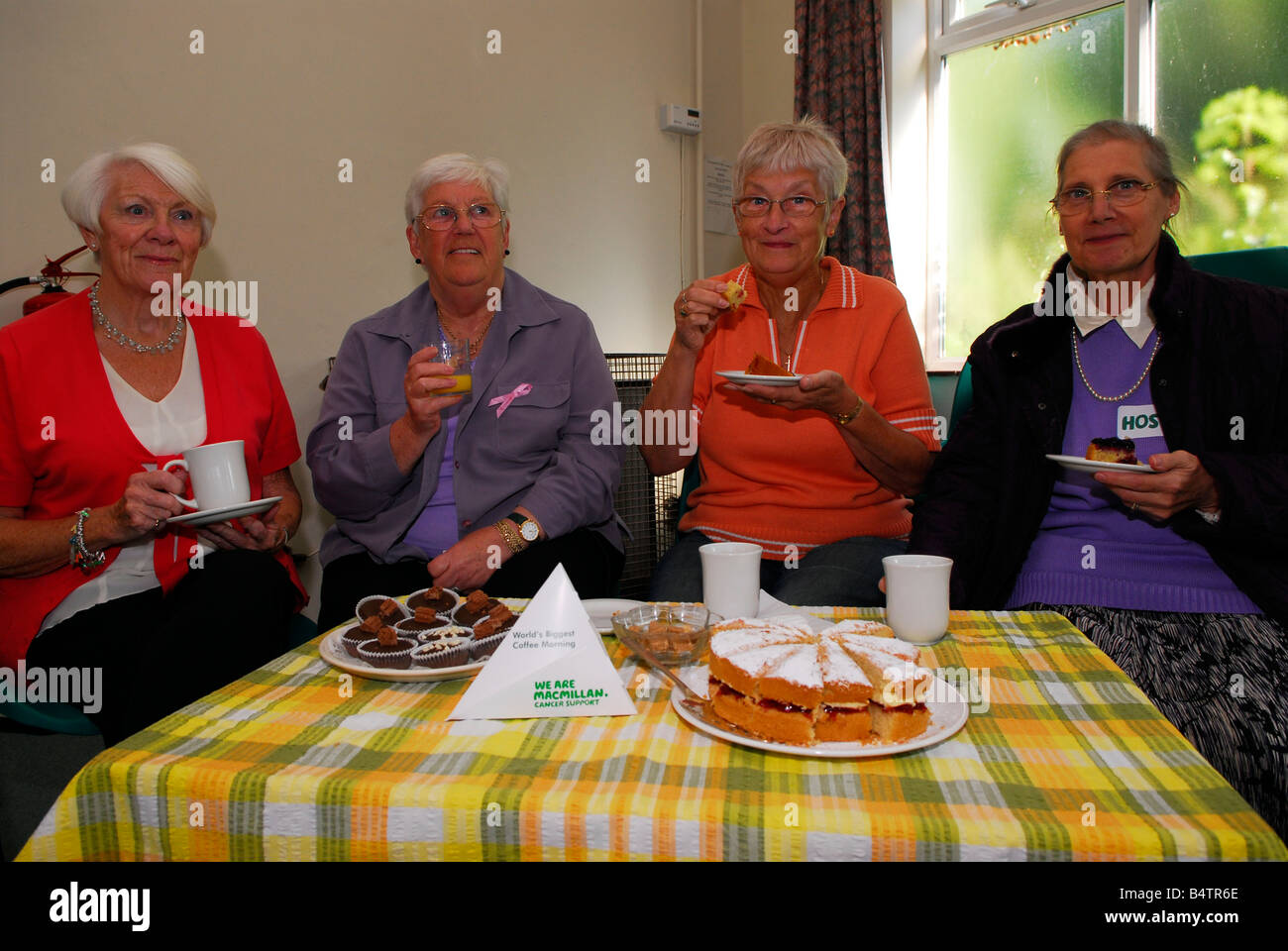 Cuatro mujeres ancianas que asisten a un café por la mañana para recaudar fondos para el cáncer Macmillan caridad, Hounslow, Middlesex, Reino Unido Foto de stock