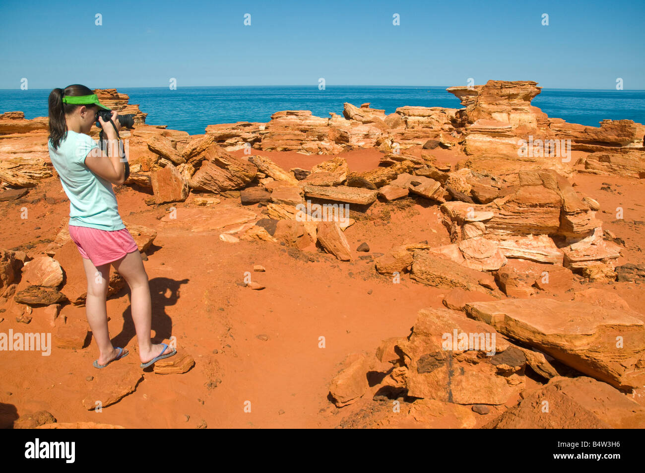Chica fotografiar las coloridas formaciones geológicas rojo en Gantheaume Point cerca de Broome, Australia Occidental Foto de stock