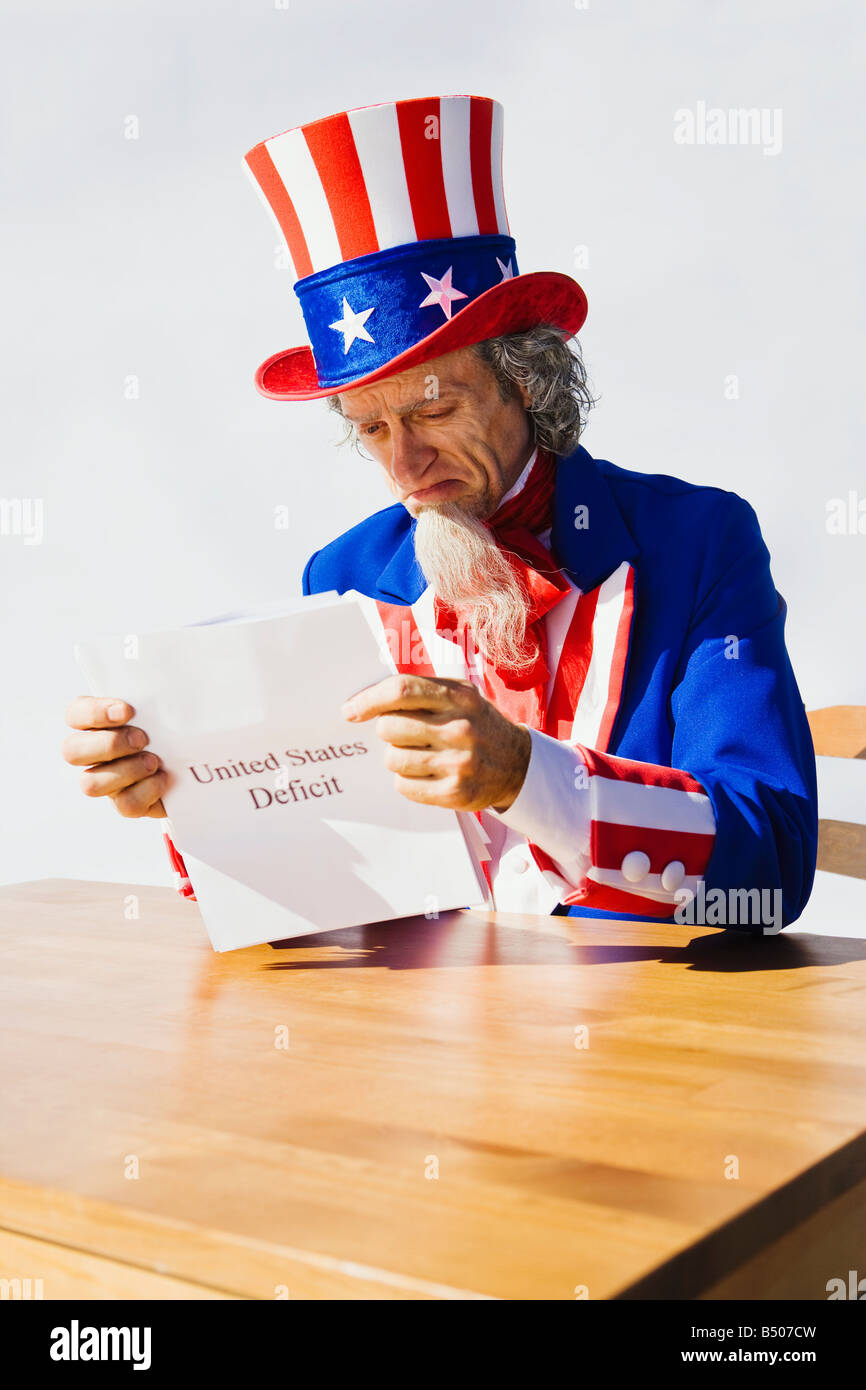 El Tío Sam sentado en una mesa mirando el déficit de los Estados Unidos Foto de stock