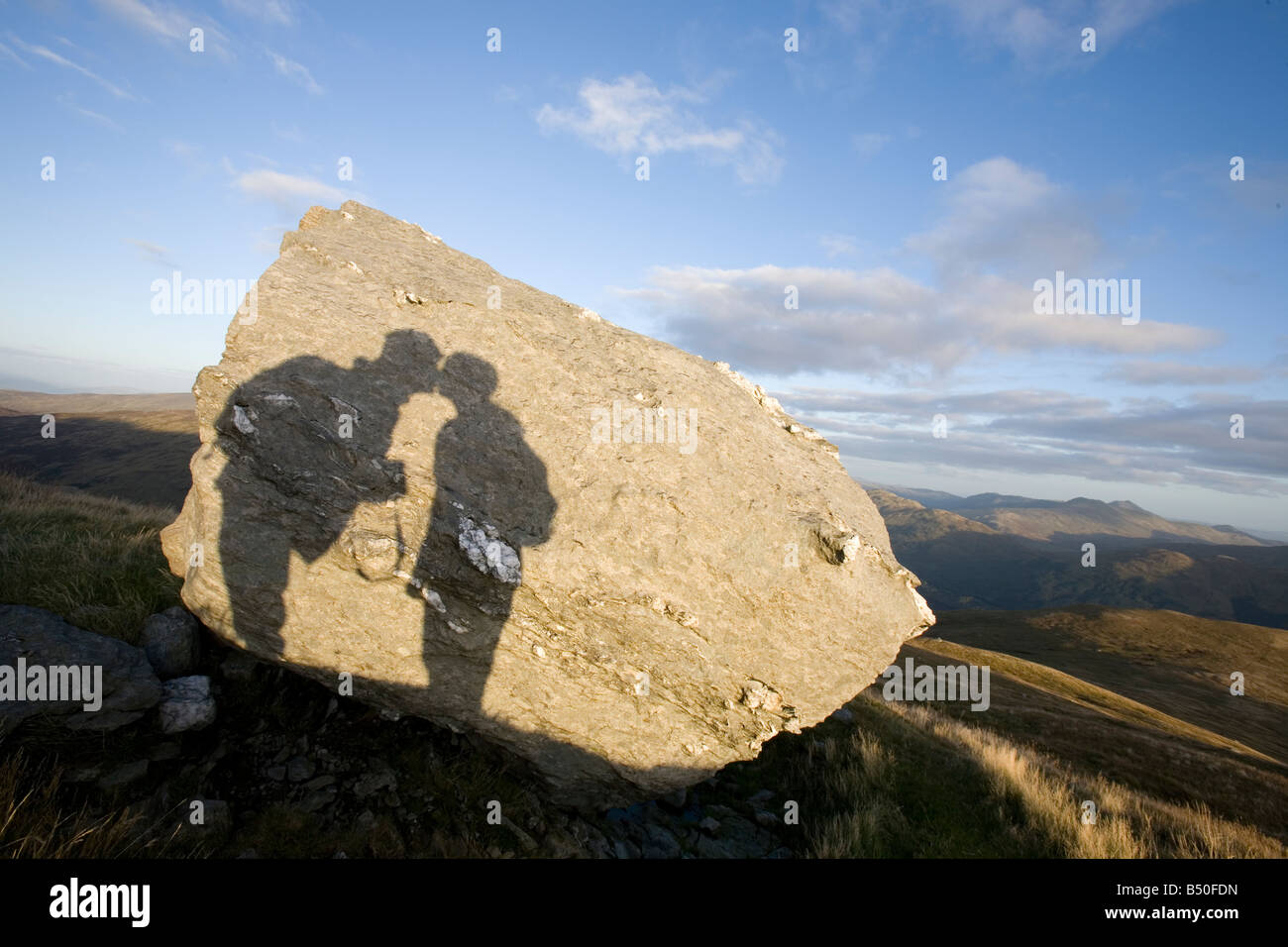 La sombra de dos personas besándose en una roca con un fondo escénico Foto de stock