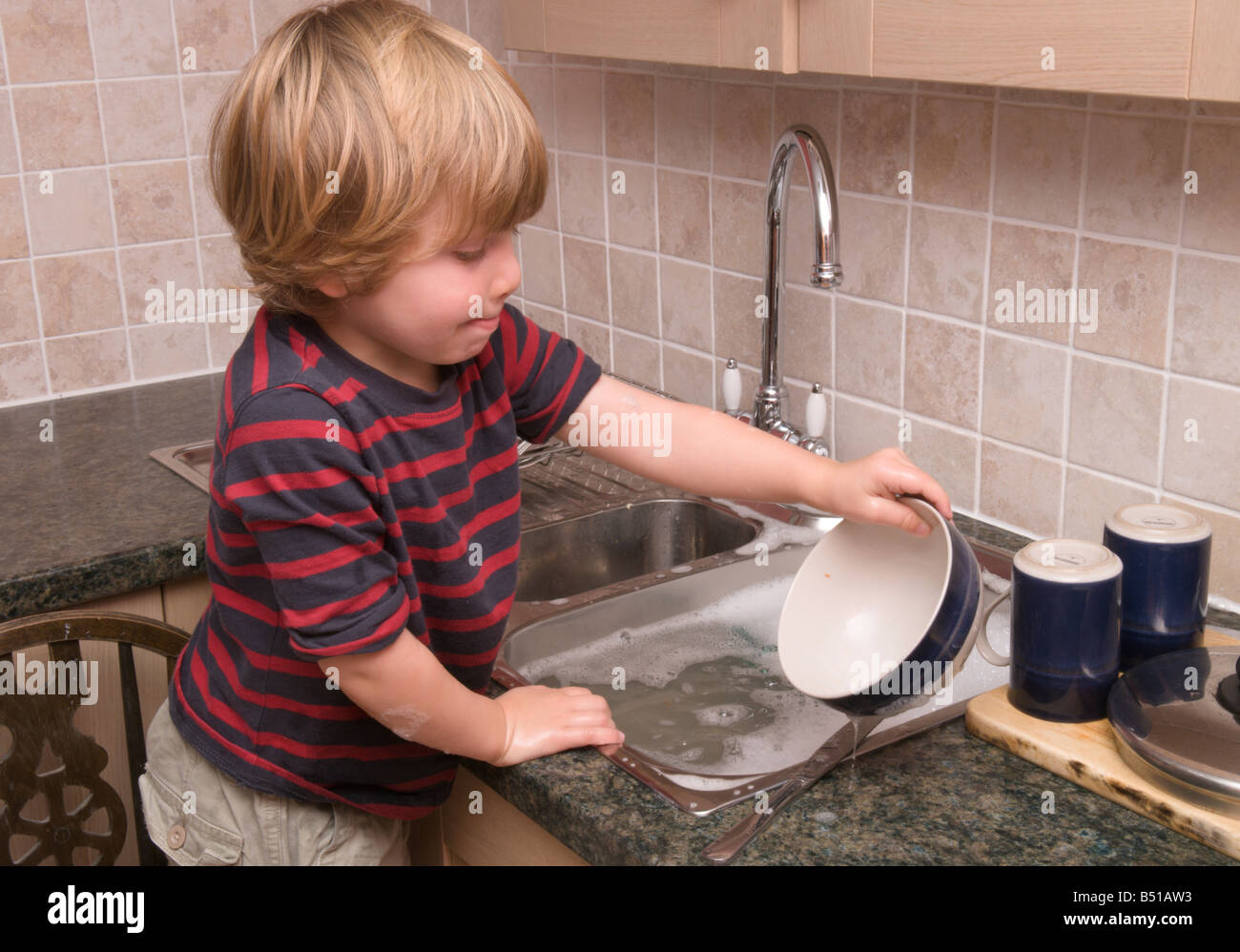 Niño niño detergente fregadero lavando los platos con agua caliente grifo  abierto Fotografía de stock - Alamy