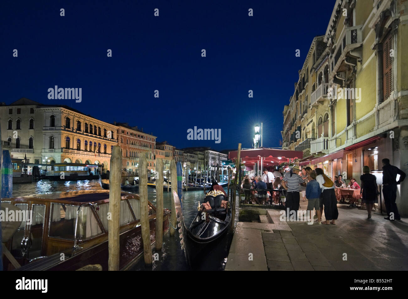 Las góndolas y restaurante por la noche en el Gran Canal, cerca del Puente de Rialto, Venecia, Véneto, Italia Foto de stock