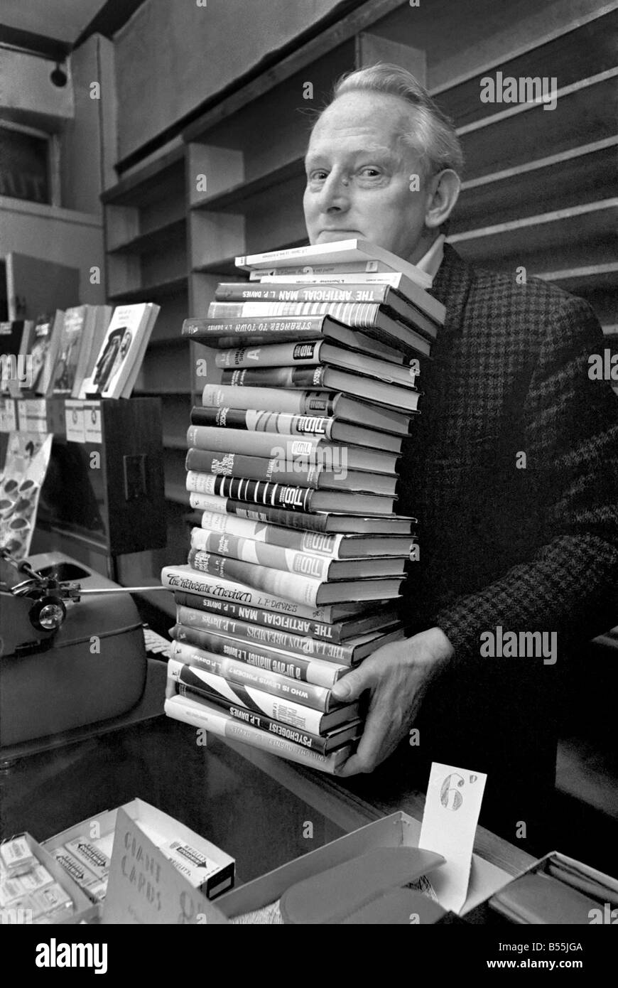 Tendero Leslie Davies en el mostrador de su tienda de tabaco y dulces en  Deganwy, con su máquina de escribir y unos pocos de los libros que ha  escrito entre vender lollipops