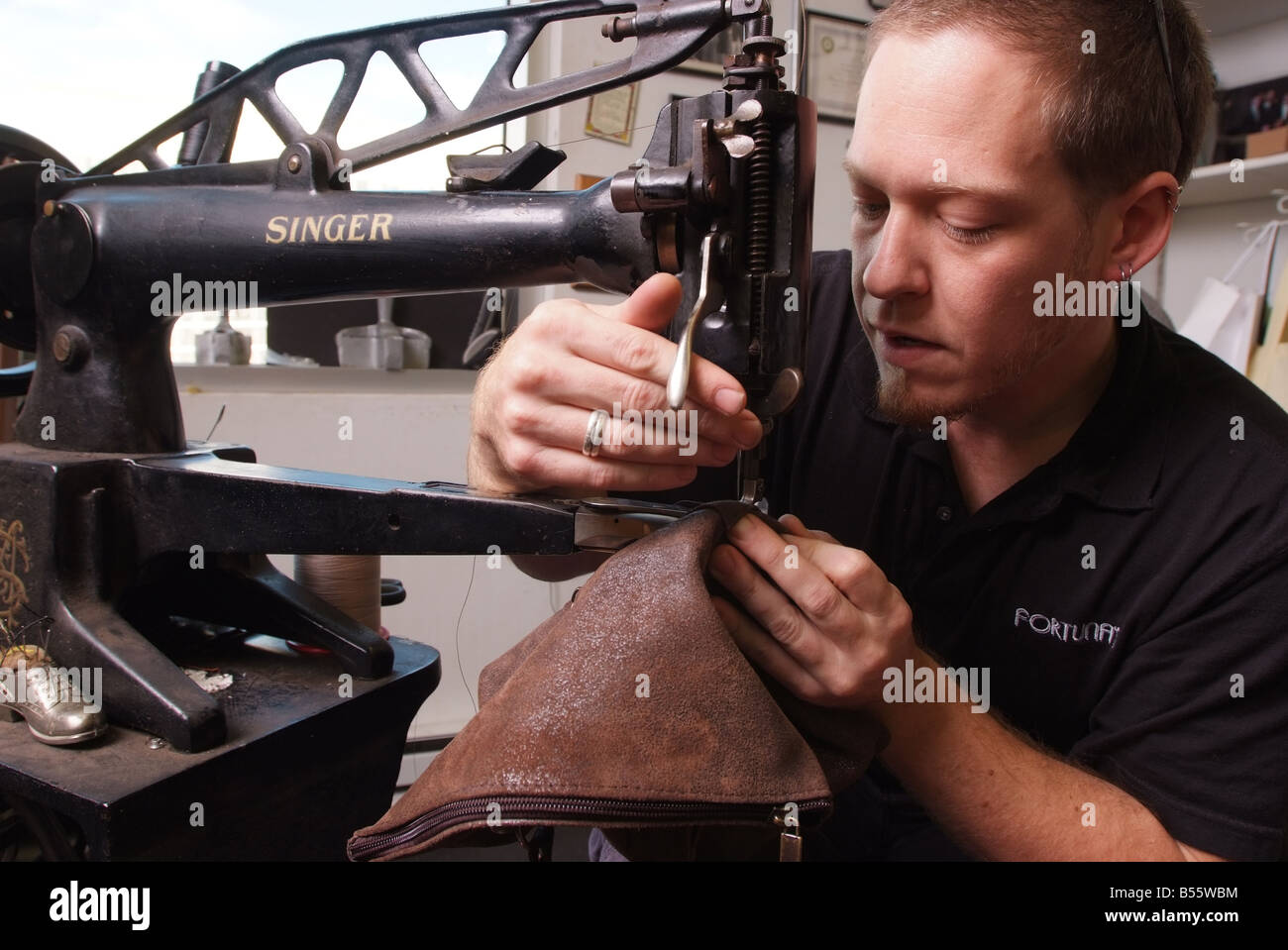 Un hombre utiliza una antigua máquina de coser Singer para la reparación de artículos de cuero en una pequeña tienda en Maryland, EE.UU. Foto de stock