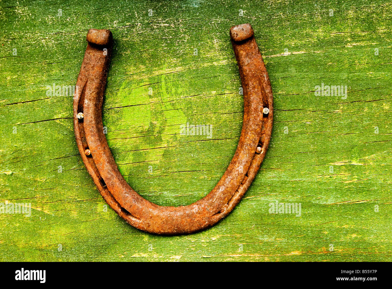 Una herradura clavada en una superficie de madera verde. Foto de stock