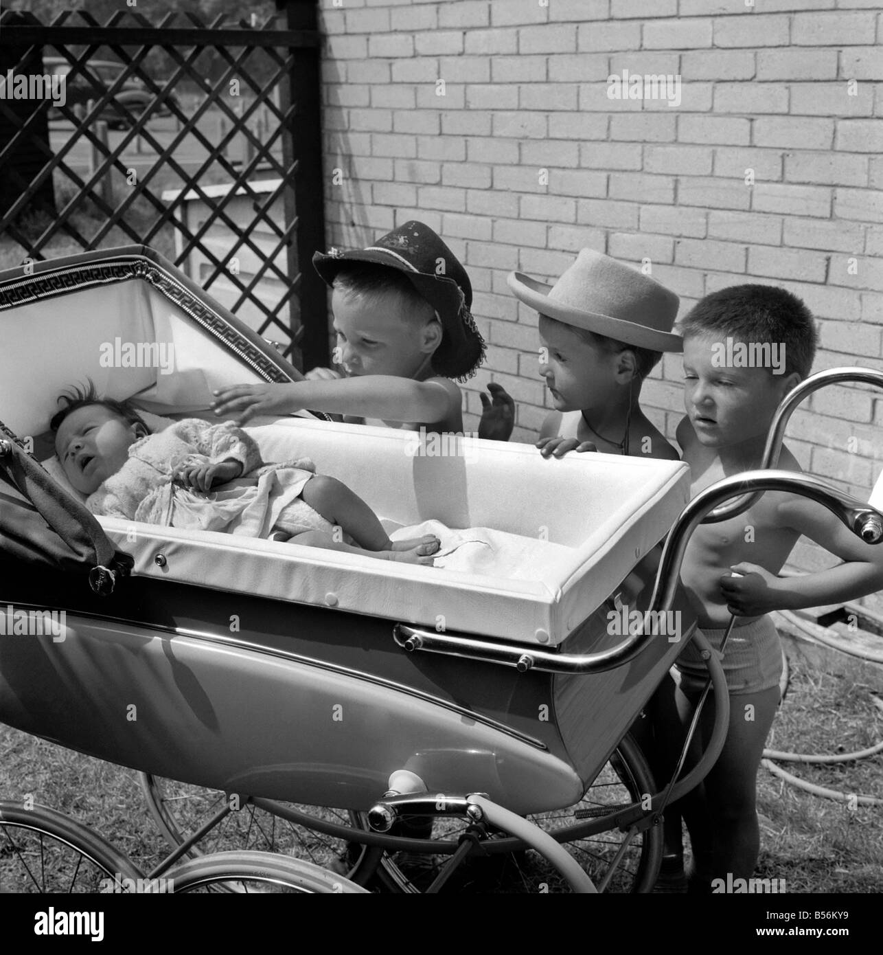 Los tres hermanos triplete de cara triste todos vestidos con sombreros de  vaqueros recostada sobre el lateral de un cochecito en el jardín de su casa  a su bebé recién nacido a