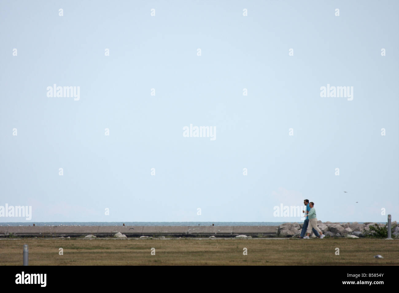 Dos personas caminando por el lago de Milwaukee a finales de verano, disfrutando del aire libre Foto de stock