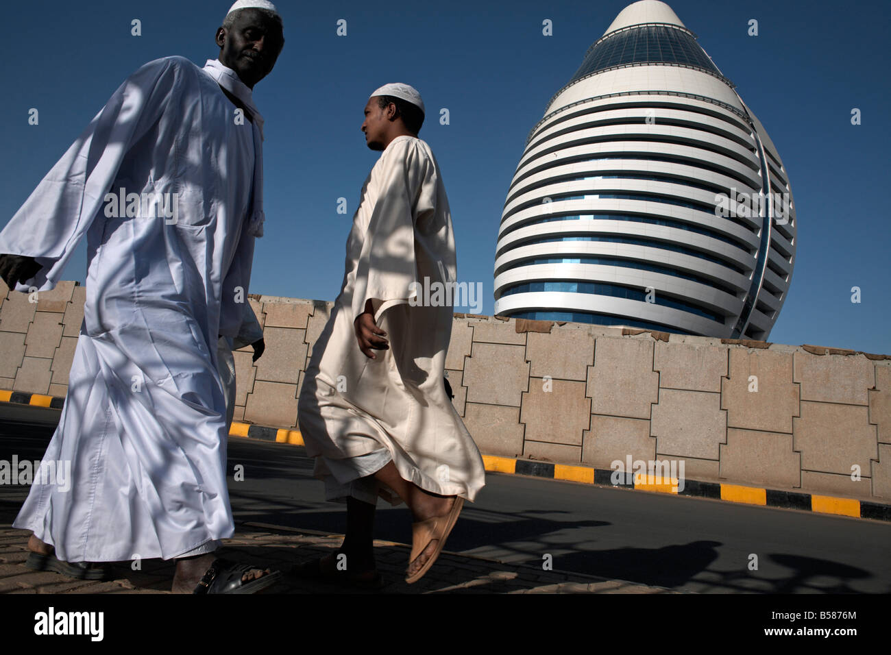 Los lugareños caminando pasado el 5 estrellas Hotel Al-Fateh Boji (Jamahiriya Hotel), diseñado para representar una vela, en Jartum, Sudán, África Foto de stock