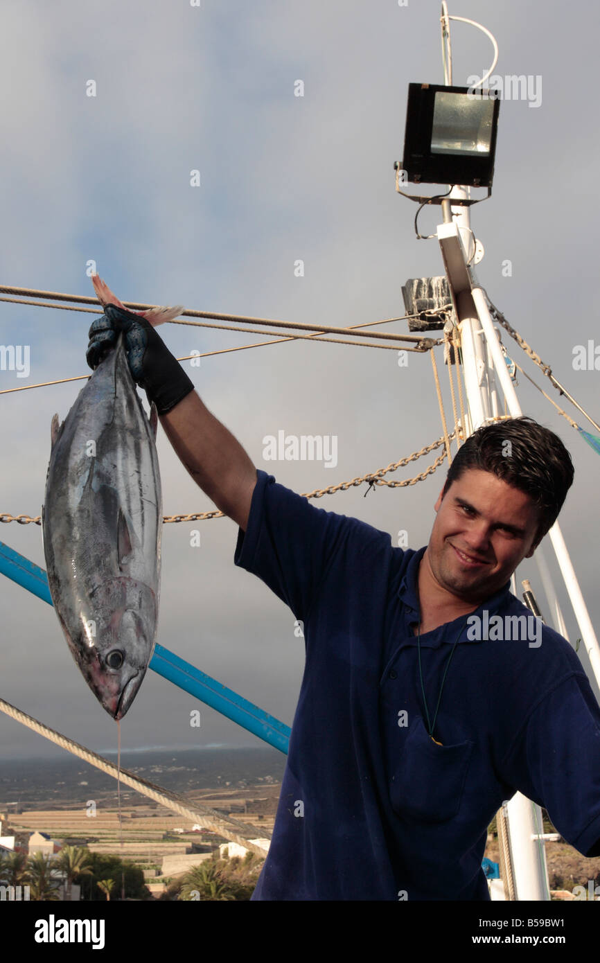 Un pescador mantiene a flote un bonito pescado recién descargadas de un barco en Playa San Juan Tenerife Islas Canarias Foto de stock