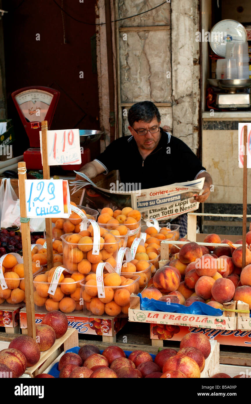 Vendedor de frutas en el mercado Ballarò, Palermo toma momento para atrapar las noticias deportivas, leyendo el periódico Corriere dello Sport Foto de stock