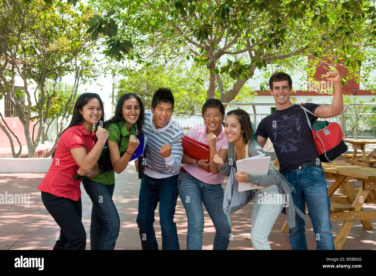 Grupo de feliz atractiva senior estudiantes adolescentes con espíritu de equipo divirtiéndose fuera el soleado patio escolar campus Foto de stock
