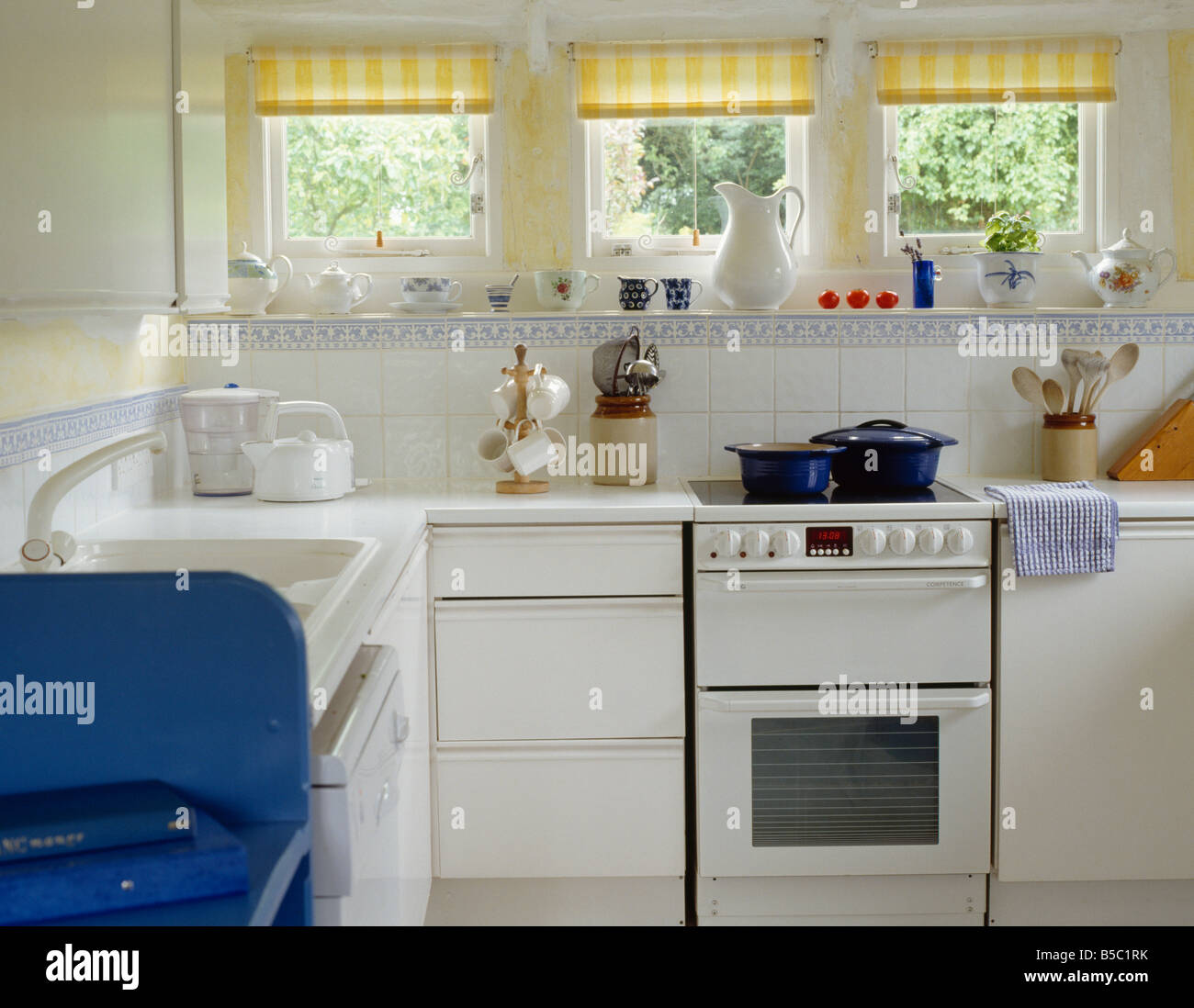 Horno Blanco en blanco unidad montada debajo de pequeñas ventanas con  persianas marcada en amarillo en la pequeña cocina del país blanco  Fotografía de stock - Alamy