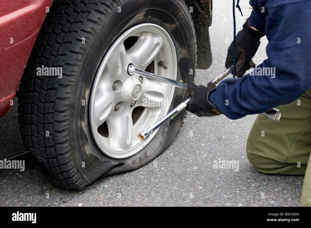 El hombre corrige una llanta desinflada, el neumático desinflado Fotografía  de stock - Alamy