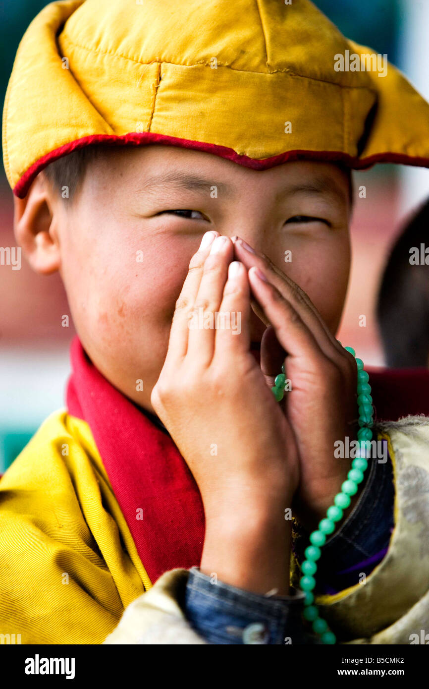 Un joven monje budista mongol mitad rezando la mitad riendo. Foto de stock