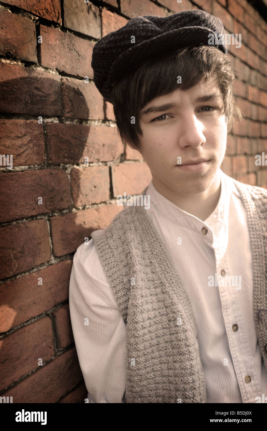 Fotografías royalty free de British Boy evacuado en permanente guerra por pared de ladrillo buscando lonely con ropa de estilo 1940. Foto de stock