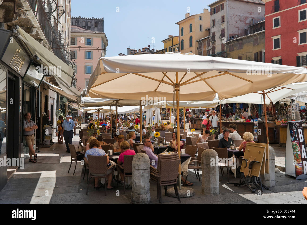 Street Cafe con puestos de mercado detrás, la Piazza delle Erbe, Verona, Véneto, Italia Foto de stock