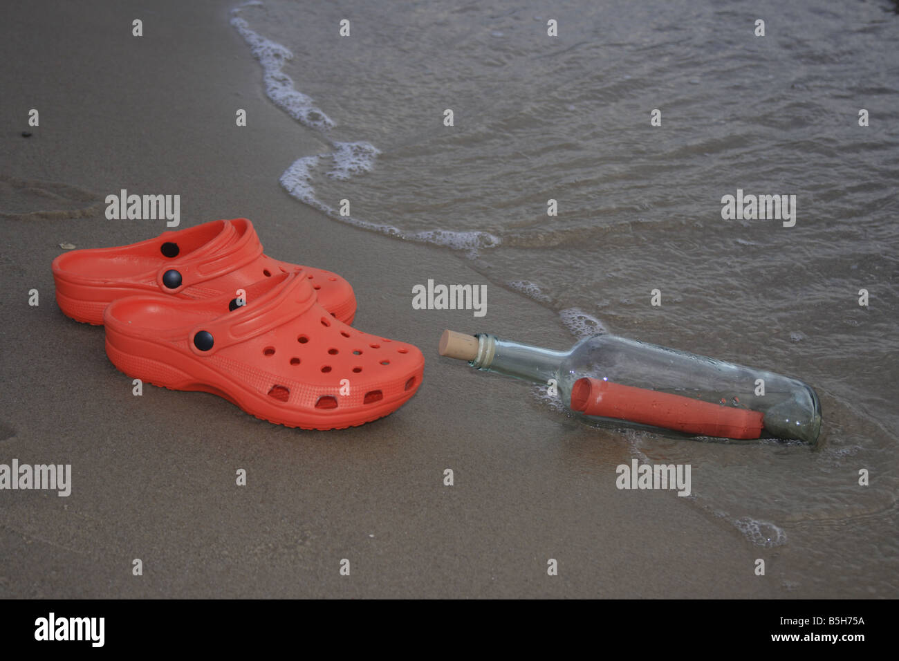 Par de crocs rojo y rojo carta como mensaje en una botella en una playa de  arena. Foto por Willy Matheisl Fotografía de stock - Alamy