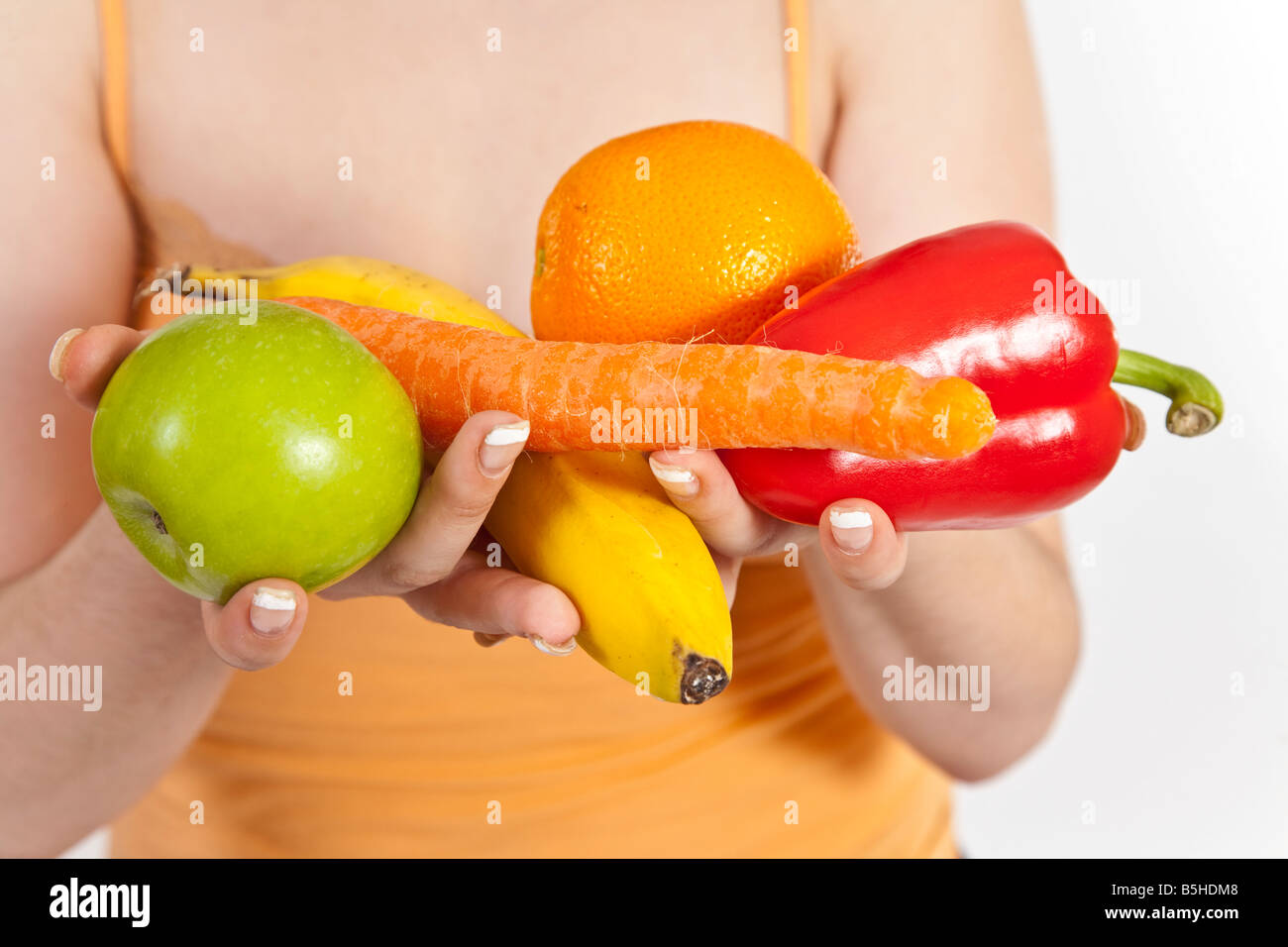 Cinco al día. Una joven sostiene cinco diferentes tipos de frutas y hortalizas. Foto de stock