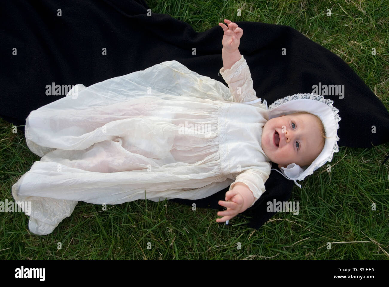 Nueve meses vestidos de niña vestidos de bautizo tradicional recostados  sobre el pasto Fotografía de stock - Alamy