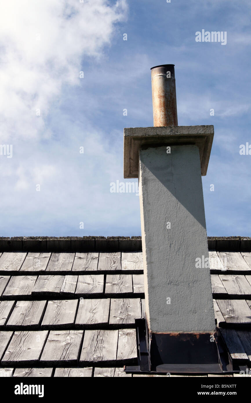 Chimenea y techo de pizarra con nublado cielo azul Foto de stock