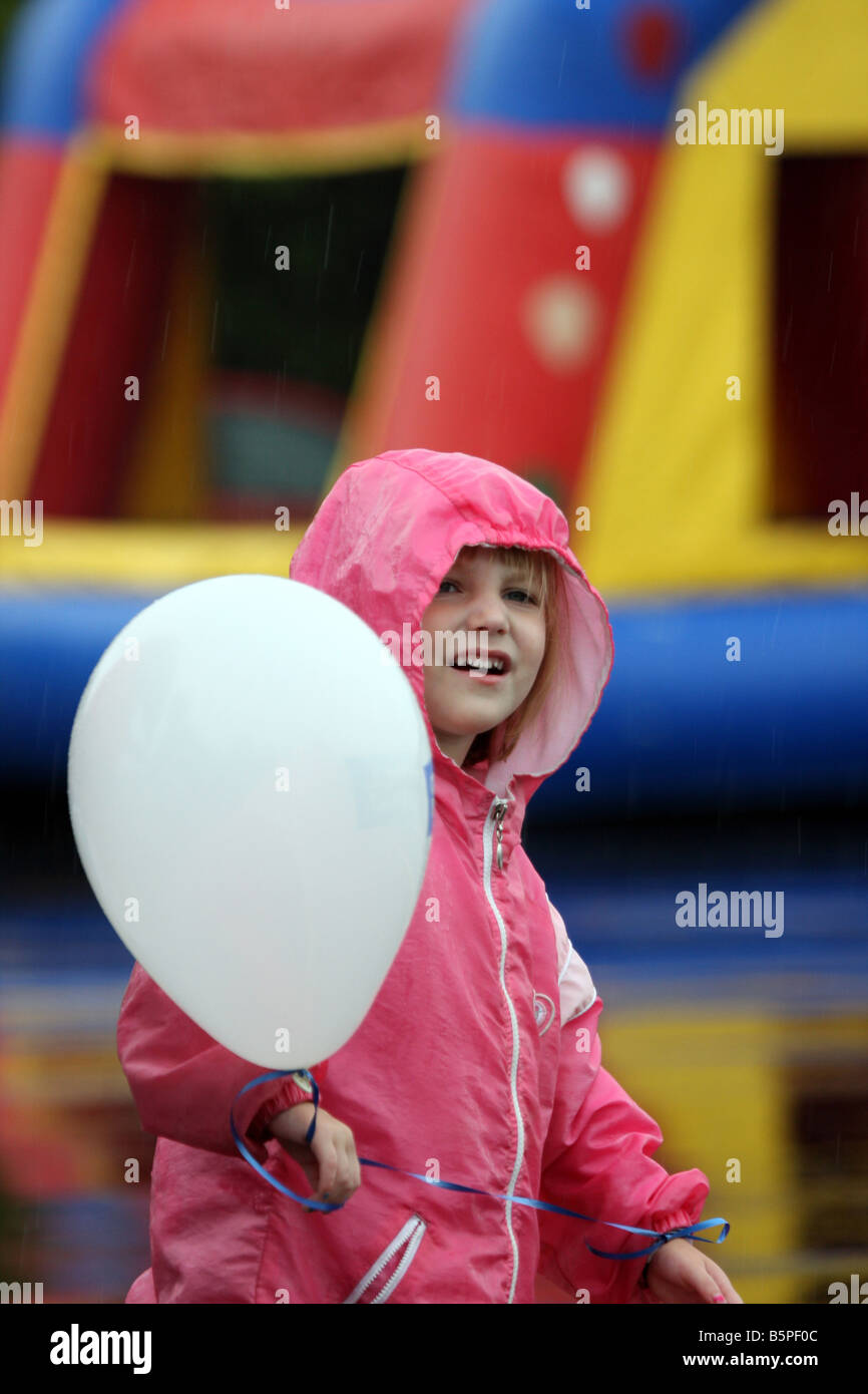 Un niño jugando con un globo en una feria sobre seguridad contra incendios en la lluvia Foto de stock