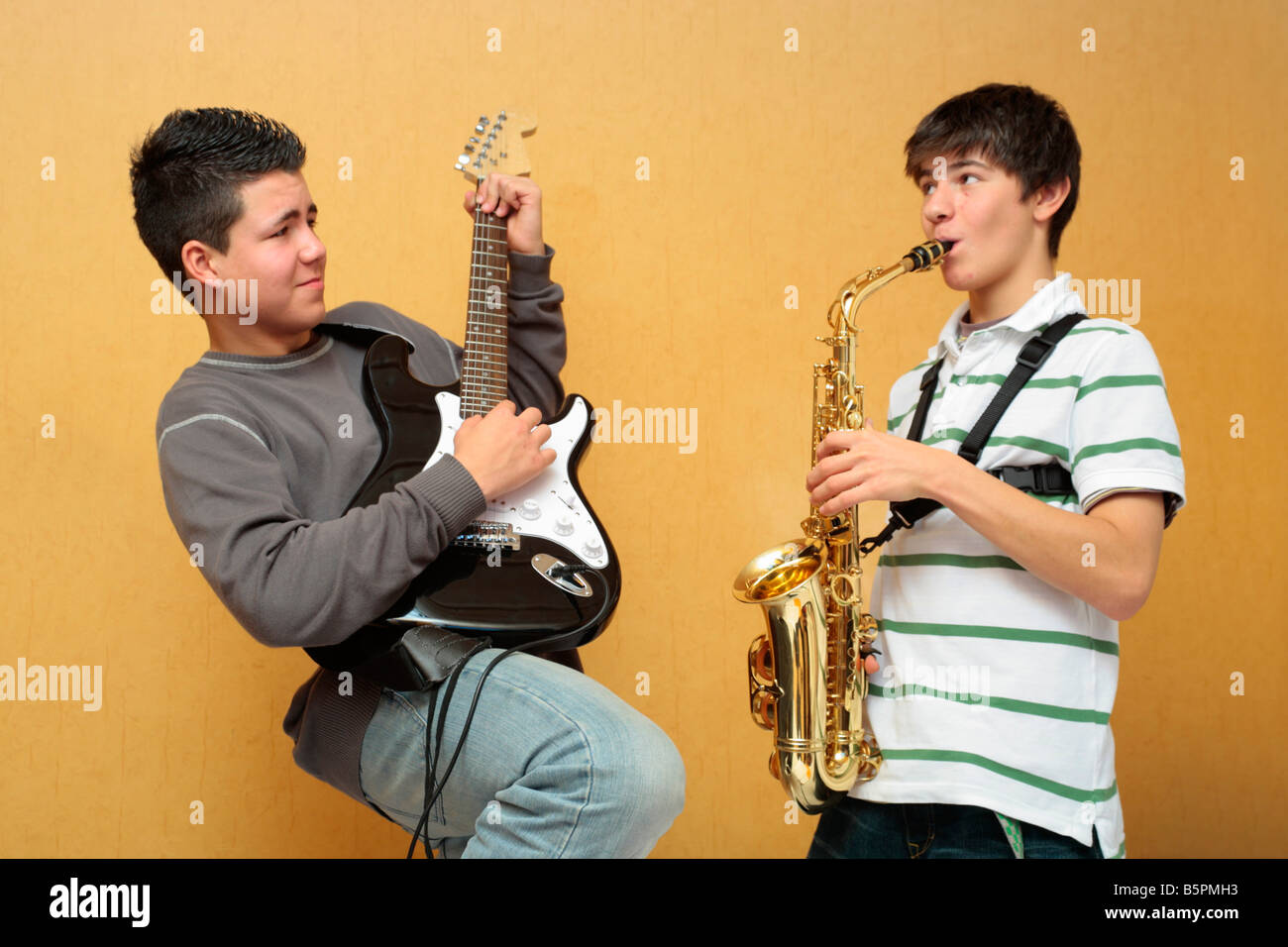 Dos muchachos adolescentes tocando la guitarra eléctrica y el saxofón  juntos Fotografía de stock - Alamy