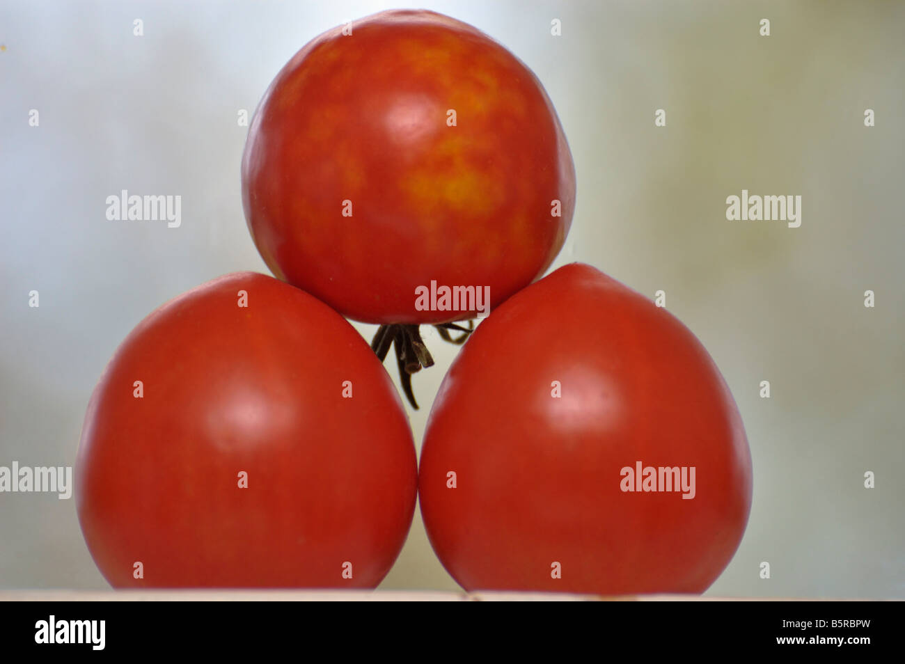 Tres tomates maduros apilados en un alféizar Foto de stock