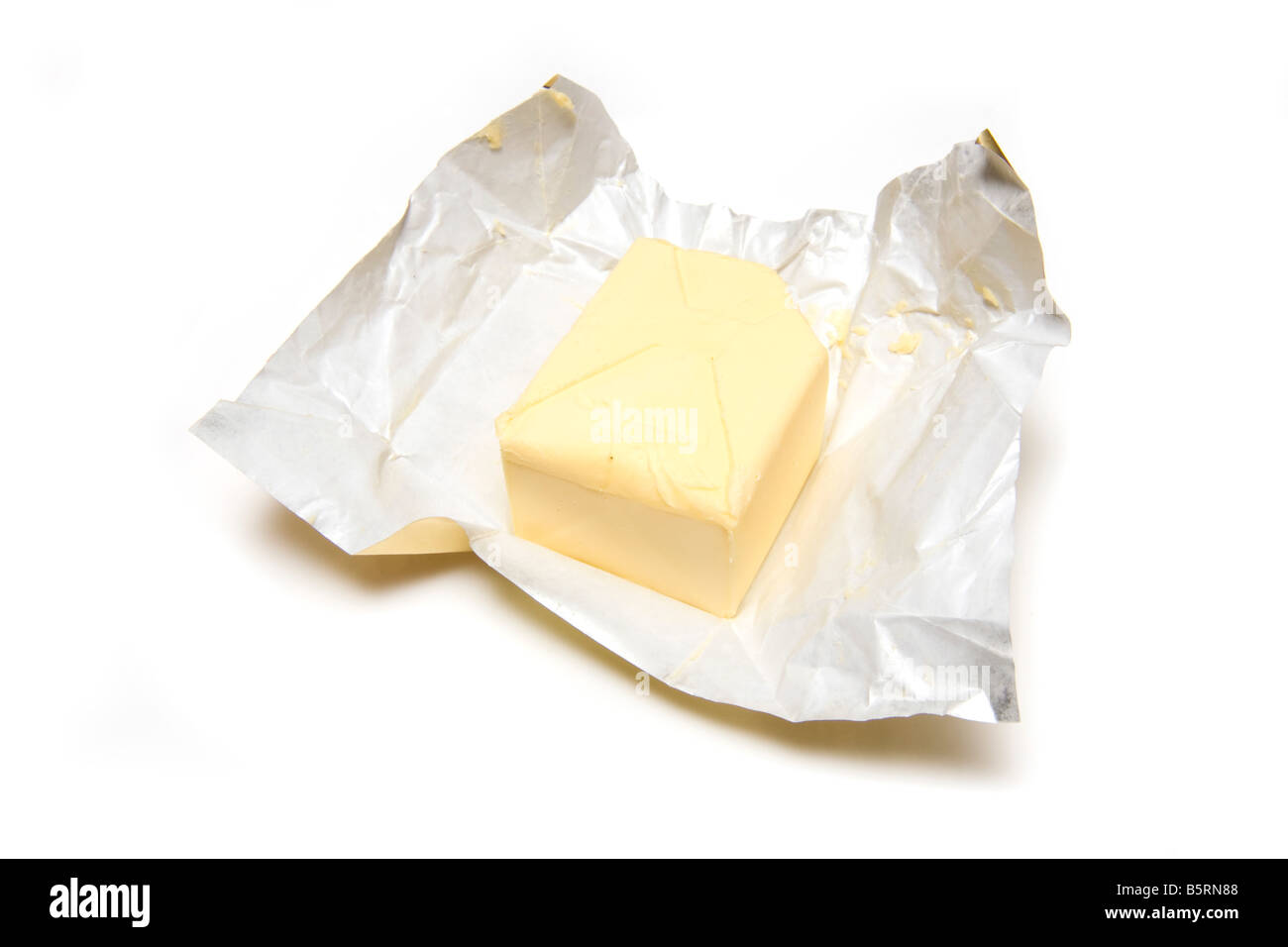 Losa de mantequilla y aislado en una envoltura de papel aluminio con fondo blanco studio Foto de stock