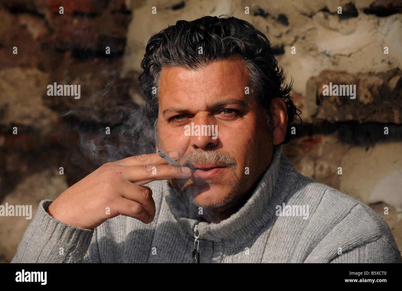 Un fornido hombre turco fuma un cigarrillo fuera de Sultanahmet, en Estambul. Foto de stock